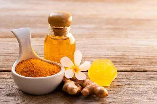 Kunyit bubuk, madu alami, dan gula batu di atas meja kayu untuk bahan minuman herbal