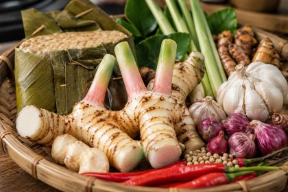 Lengkuas segar di tampah bambu bersama tempe dan bumbu dapur tradisional