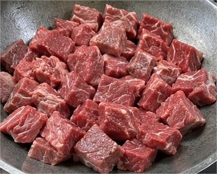 Potongan daging sapi segar untuk bahan rendang Padang yang siap dimasak dengan bumbu rempah dan santan.