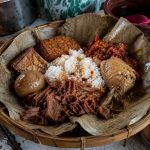 Gudeg Jogja tradisional dengan ayam kampung, telur pindang, tahu bacem, tempe bacem, dan sambal krecek di atas daun jati