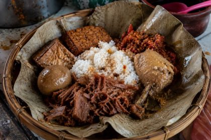 Gudeg Jogja tradisional dengan ayam kampung, telur pindang, tahu bacem, tempe bacem, dan sambal krecek di atas daun jati