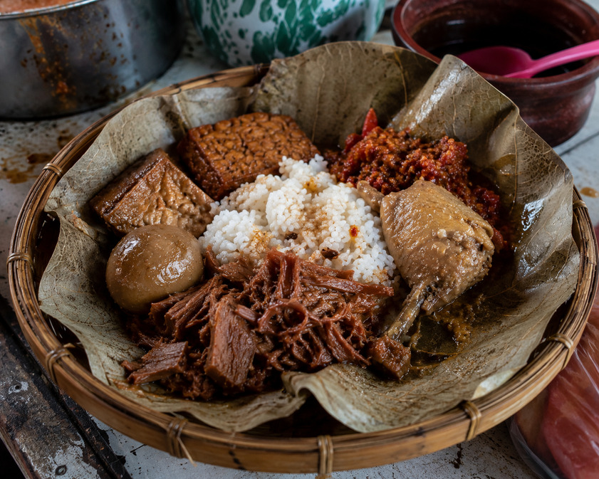 Gudeg Jogja tradisional dengan ayam kampung, telur pindang, tahu bacem, tempe bacem, dan sambal krecek di atas daun jati