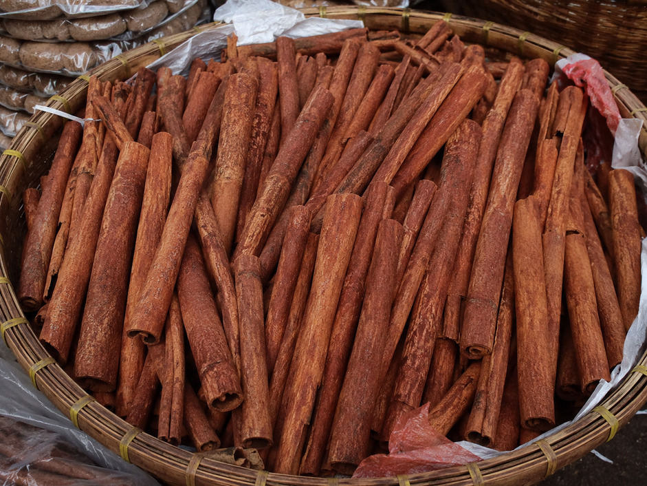 Kumpulan batang kayu manis berkualitas tinggi dalam nampan bambu di pasar rempah tradisional