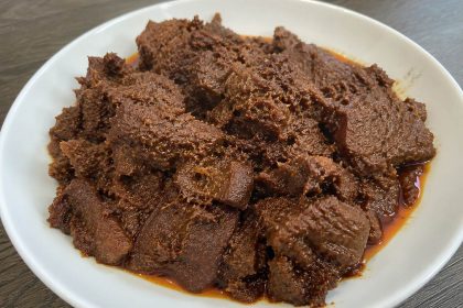 Rendang daging sapi Padang asli dengan bumbu rempah khas Minangkabau yang meresap, disajikan di atas piring putih.