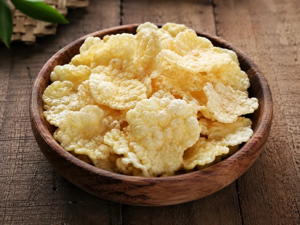 Emping melinjo renyah dalam mangkuk kayu sebagai pelengkap Soto Betawi dan berbagai makanan khas Indonesia.
