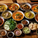 Sajian macam-macam gulai khas Indonesia lengkap dengan nasi putih, sambal, lalapan, kerupuk, dan aneka kondimen di atas meja makan.