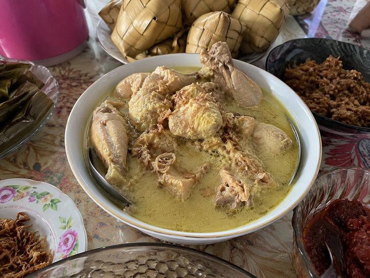 Opor ayam kuah santan gurih siap disajikan dengan taburan bawang goreng, ketupat, dan sambal khas menu Lebaran.