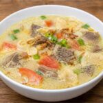 Semangkuk Soto Betawi khas Jakarta dengan kuah santan gurih, potongan daging sapi, tomat, daun bawang, bawang goreng, dan emping.