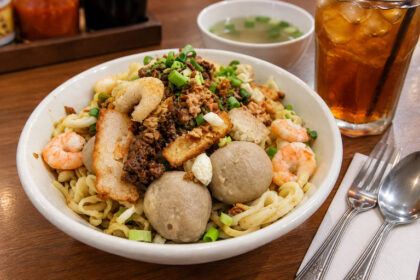 Semangkuk Bakmi Singkawang dengan topping udang, bakso, daging cincang, daun bawang, dan es teh