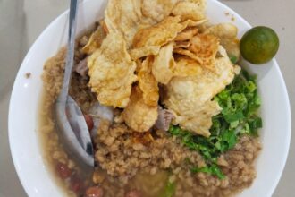 Bubur Pekong khas Singkawang dengan daging sapi, kerupuk goreng, kacang, daun bawang, dan jeruk limau dalam kuah kaldu gurih