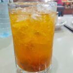 Es Nammong khas Singkawang berwarna kuning keemasan disajikan dalam gelas tinggi dengan es batu, tampak segar dan dingin di atas meja restoran.