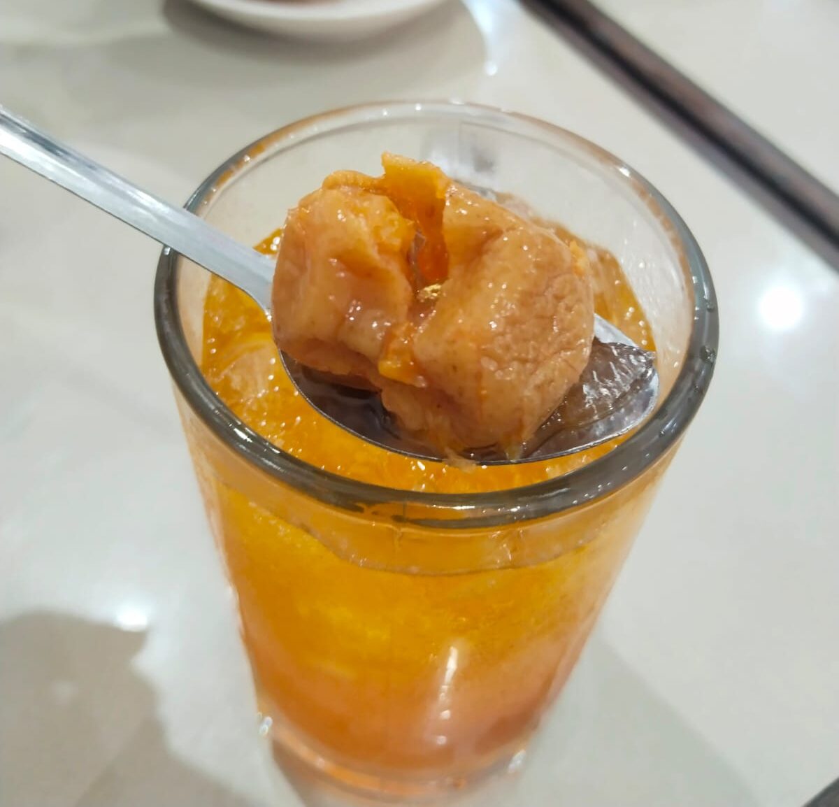 Es Nammong khas Singkawang berwarna kuning keemasan dengan es batu dan potongan jeruk Nammong di atasnya.