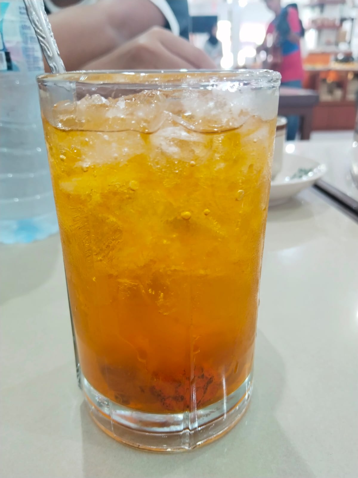 Es Nammong khas Singkawang berwarna kuning keemasan disajikan dalam gelas tinggi dengan es batu, tampak segar dan dingin di atas meja restoran.