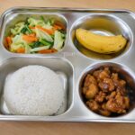 Menu MBG murah berupa nasi putih, ayam kecap, tumis sayuran wortel dan kol, serta pisang dalam wadah ompreng stainless steel