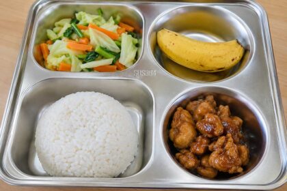 Menu MBG murah berupa nasi putih, ayam kecap, tumis sayuran wortel dan kol, serta pisang dalam wadah ompreng stainless steel