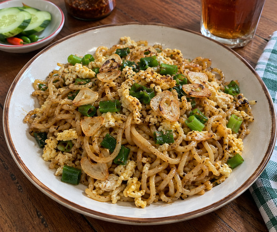 Mie goreng bawang putih dengan telur, daun bawang, dan bawang goreng