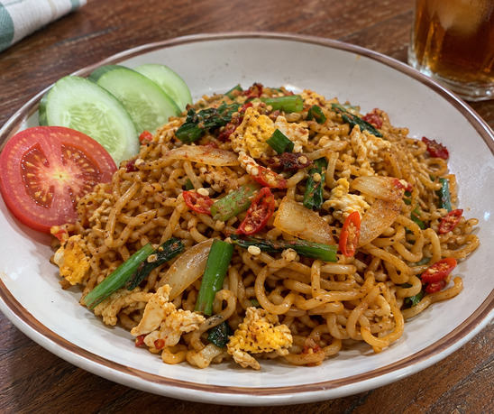 Mie goreng pedas manis dengan telur, cabai, dan daun bawang