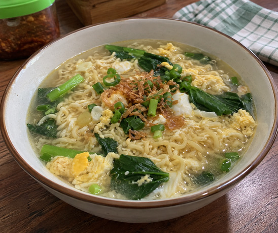 Mie kuah telur dengan sawi, daun bawang, dan bawang goreng